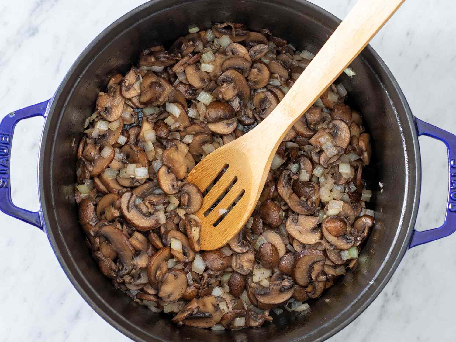 Sliced mushrooms browning in a large pot with onions and thyme